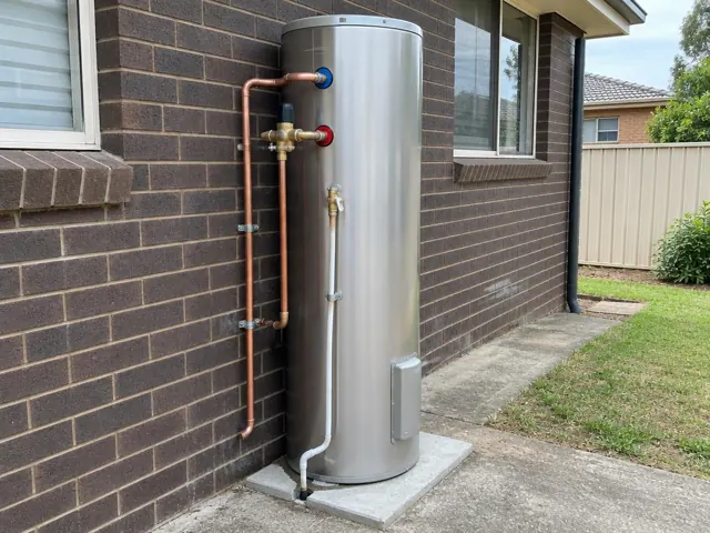 Outdoor hot water system on a concrete slab beside a brick house wall in Greystanes